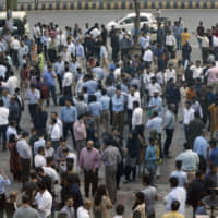 People stand outside their offices after an earthquake is felt in Islamabad on Tuesday. | AP