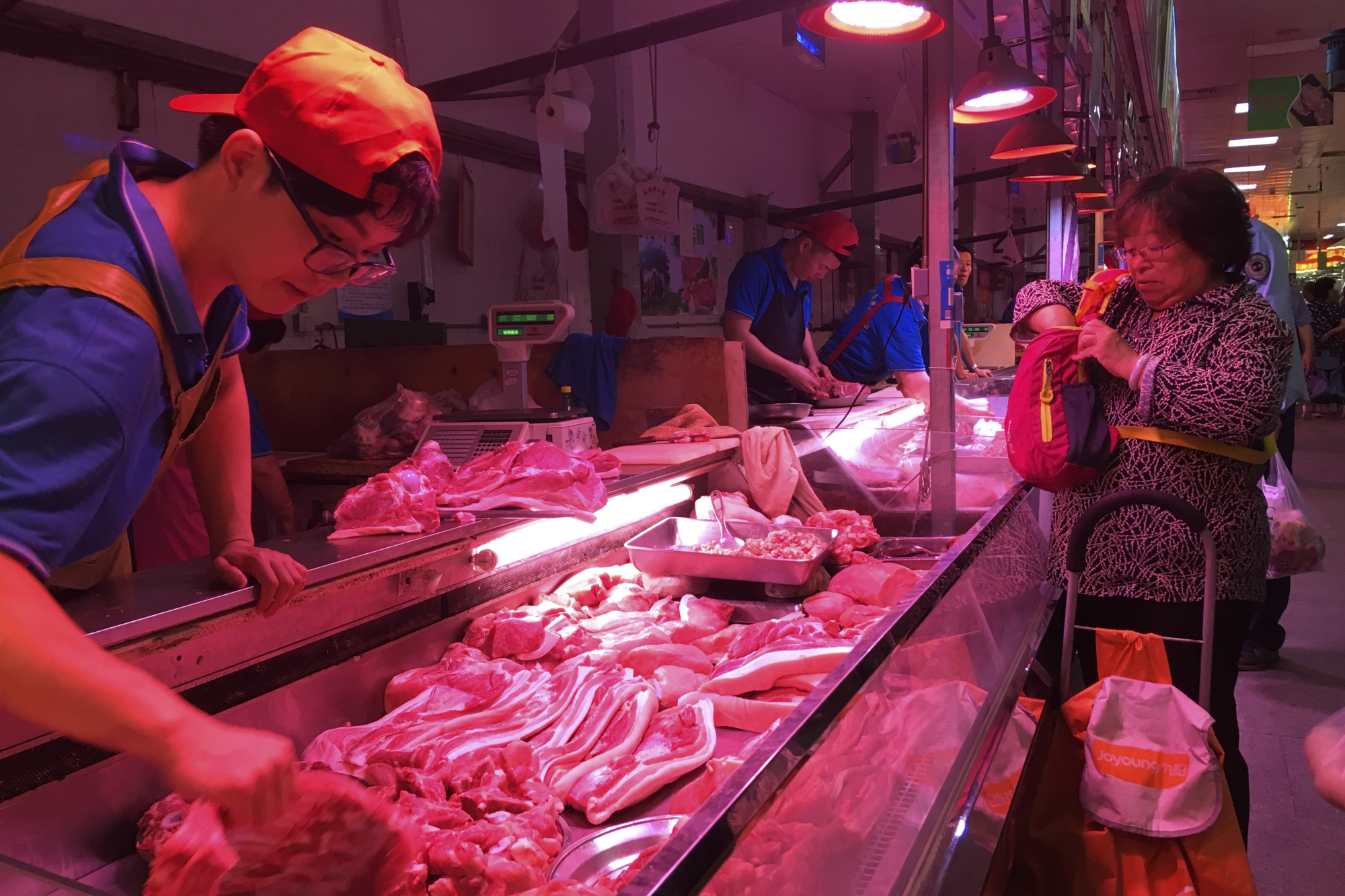 A clerk stacks cuts of pork at a meat market in Beijing on Sept. 11. | AP