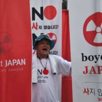 A protester holds anti-Japanese banners during a rally in Seoul on Aug. 3 against Tokyo\'s decision to remove South Korea from a so-called white list of favored export partners. | AFP-JIJI