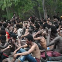Migrants are arrested after they force their way into the Spanish territory of Ceuta on Aug. 30. Over 150 migrants made their way into Ceuta after storming a barbed-wire border fence with Morocco. | AFP-JIJI