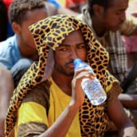 An Irregular migrant who was abandoned by traffickers in a remote desert area near the Libyan border drinks water as he waits to be transported after being located and arrested by Sudan\'s paramilitary Rapid Support Forces (RSF) on the Khartoum State border, Sudan, Wednesday. | REUTERS