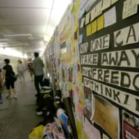 People walk past slogans from a \"Lennon Wall\" exhibition in Taipei on Aug. 31. The event supported Hong Kong\'s pro-democracy protests. | AP
