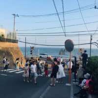 Tourists take photos next to a railway crossing near Kamakura High School that appeared in the hit Japanese anime \"Slam Dunk.\" | COURTESY OF GUAN HUIWEN