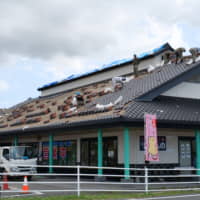 Repair workers fix roof tiles on a house in Minamiboso, Chiba Prefecture, on Sept. 25. The tiles were blown off by strong winds from Typhoon Faxai when the storm passed over the area earlier this month. | CHISATO TANAKA