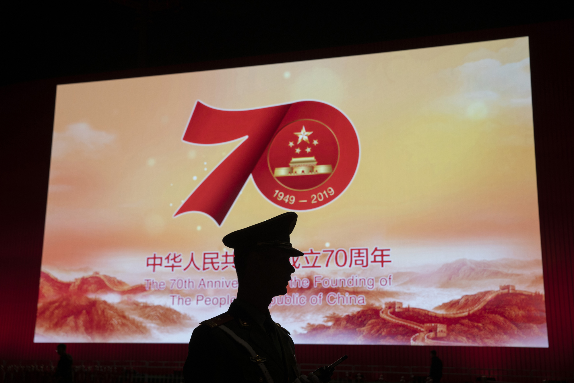 A Chinese paramilitary policeman is silhouetted by a display related to the upcoming 70th anniversary of the founding of the People's Republic of China, in Beijing on Saturday. | AP