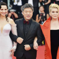Flanked by Juliette Binoche and Catherine Deneuve, director Hirokazu Kore-eda walks the red carpet ahead of a screening of the \"The Truth\" and the opening ceremony of the 76th Venice Film Festival, at Sala Grande in Venice, Italy, on August 28. | GETTY IMAGES / VIA KYODO