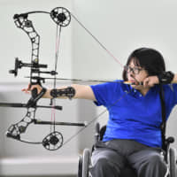 Aiko Okazaki, who has been selected to compete in the Tokyo Paralympics, draws a compound bow at an archery hall in Tokyo in July. | KYODO