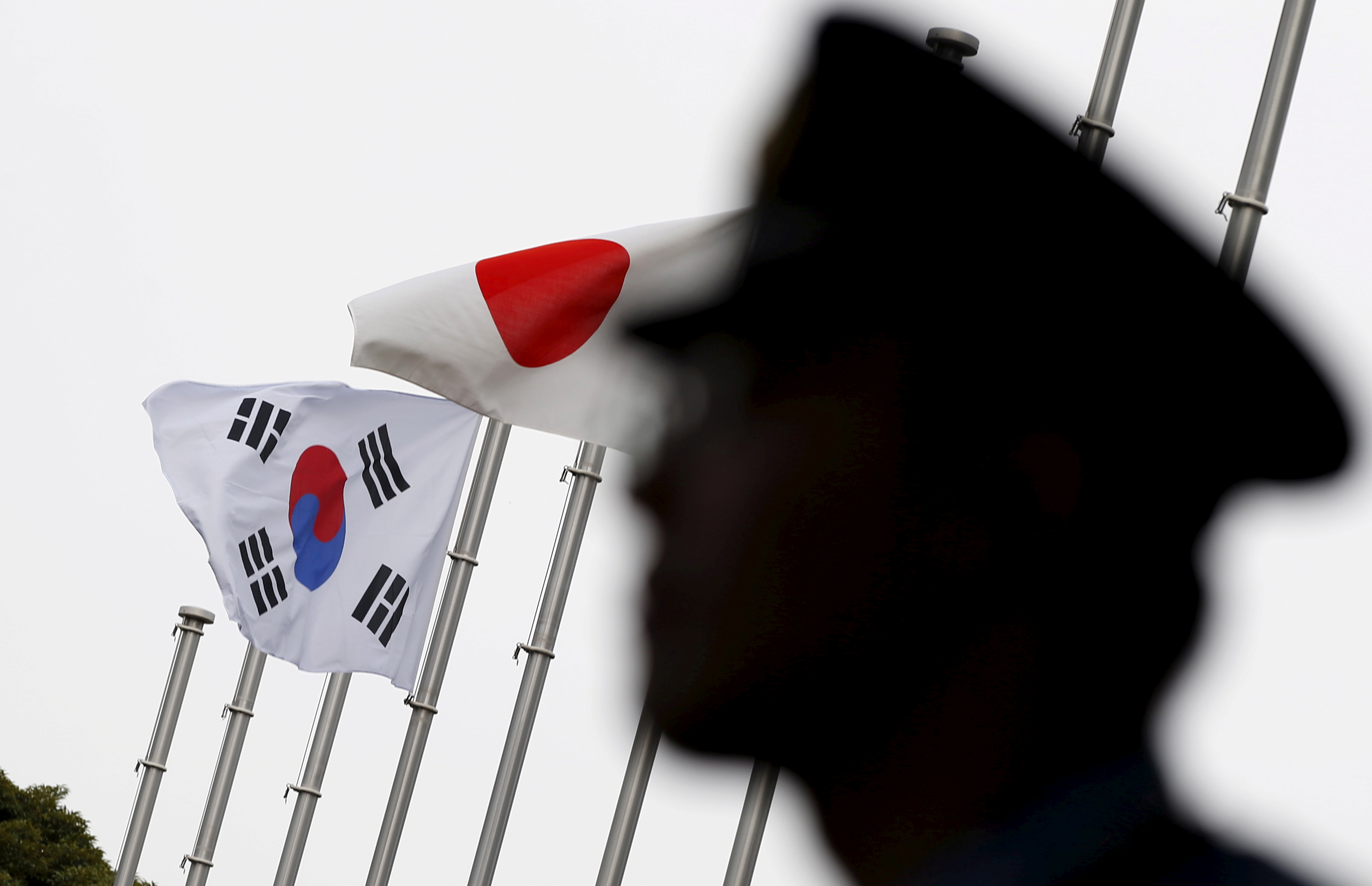A police officer stands guard near Japanese and South Korean national flags at a hotel where the South's Embassy in Japan held a reception to mark the 50th anniversary of normalization of ties between Seoul and Tokyo, in the Japanese capital in June 2015.   | REUTERS