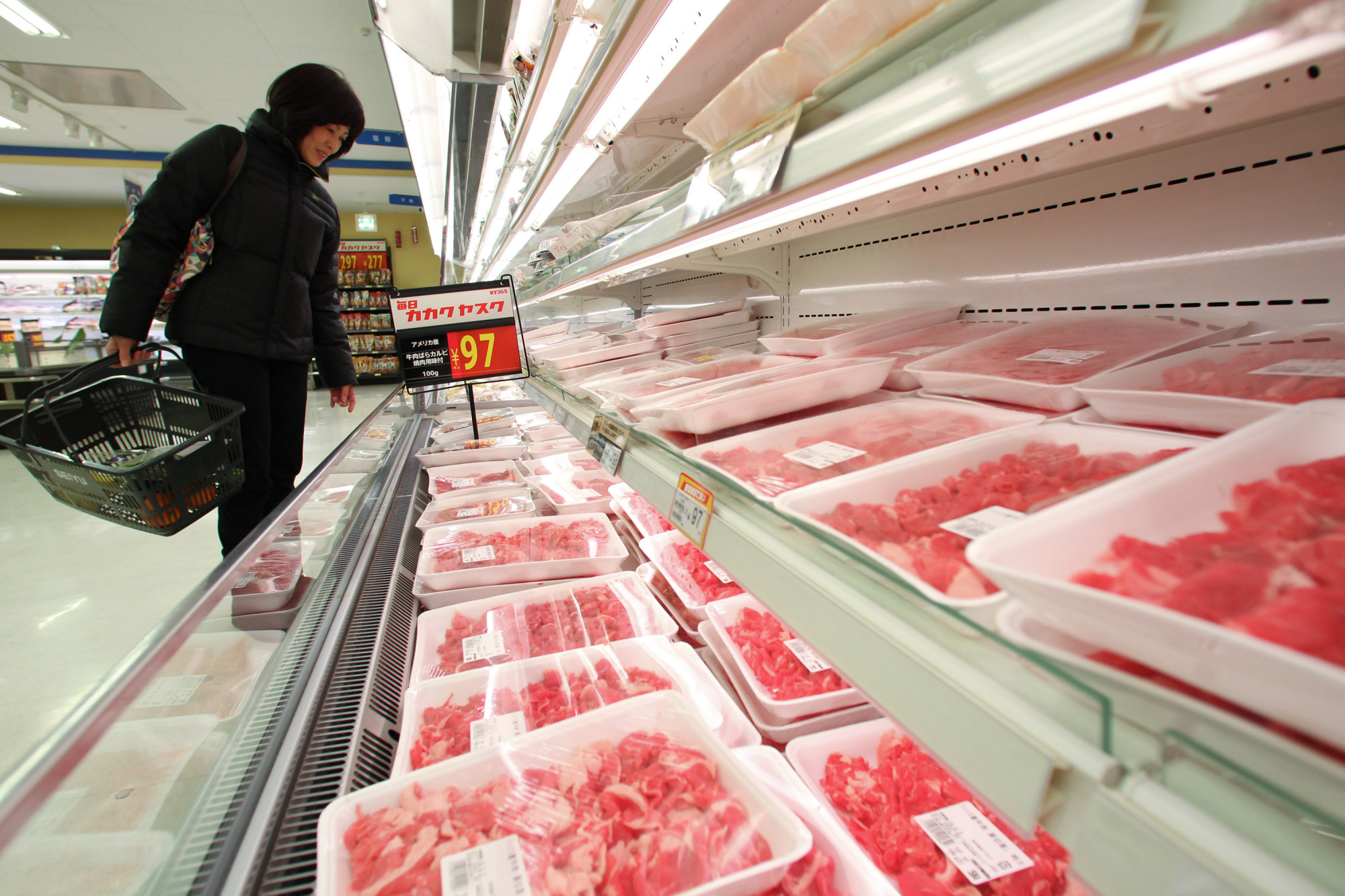 A woman looks at American beef on sale in a Seiyu supermarket in 2013. In its current round of bilateral trade negotiations with the United States, Japan has agreed to lower tariffs on American beef and increase import quotas. | BLOOMBERG