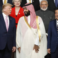 U.S. President Donald Trump speaks with Saudi Crown Prince Mohammed bin Salman during a family photo session at the Group of 20 summit in Osaka on June 28. | BLOOMBERG