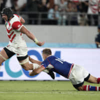 Japan\'s Pieter Labuschagne breaks the tackle of Russia\'s Yury Kushnarev on his way to scoring a try during the Rugby World Cup opening game at Tokyo Stadium on Friday night. Japan defeated Russia 30-10. | AP