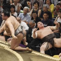 Yokozuna Hakuho (right) reacts after being defeated by Hokutofuji on the opening day of the Autumn Grand Sumo Tournament on Sunday at Ryogoku Kokugikan. | KYODO