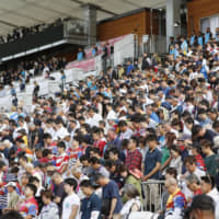 Fans at Kamaishi Unosumai Recovery Memorial Stadium bow their heads in prayer during a moment of silence before Wednesday\'s Rugby World Cup match between Uruguay and Fiji. | KYODO