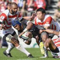 Japan captain Michael Leitch (left) and Kenki Fukuoka (second from right) tackle a Fijian player during their Pacific Nations Cup match on July 27 at Kamaishi Unosumai Recovery Memorial Stadium in Iwate Prefecture. | KYODO