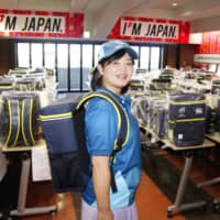 A volunteer in Kumagaya, Saitama Prefecture, shows off the uniform and backpack that will be used by 13,000 \'Team No-Side\' members during the 2019 Rugby World Cup. | KYODO