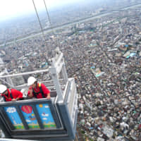 Takuma Tachibana (left) and another worker clean the windows of Tokyo Skytree, the world\'s tallest tower, in Sumida Ward earlier this month. Dangling 450 meters above the ground, Tachibana says he counts himself lucky to be up there with a panoramic view. | CHISATO TANAKA