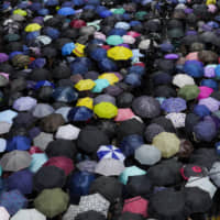 Protesters march in the rain on a street in Hong Kong Sunday. | AP