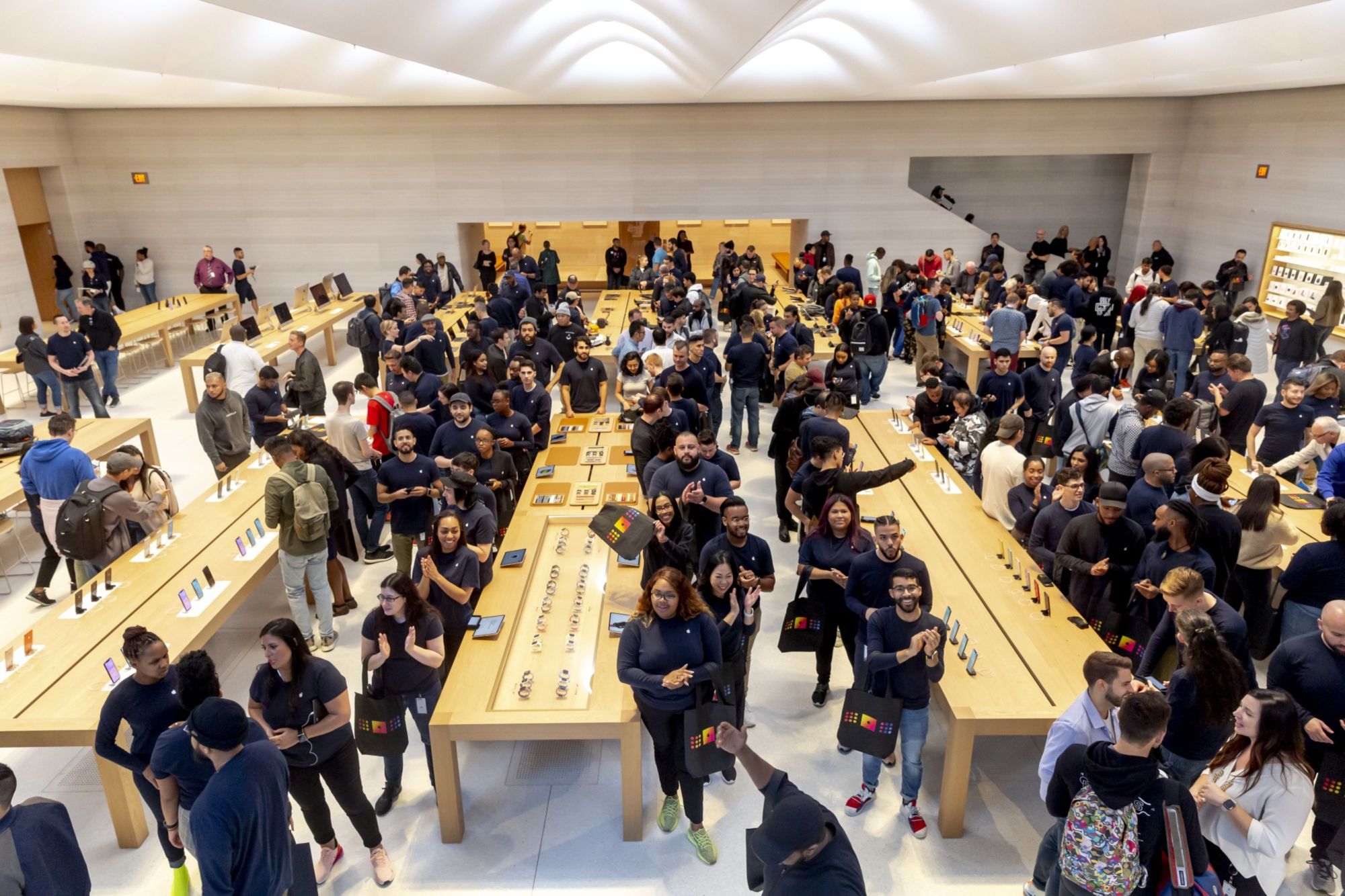 During an event held for Apple's latest iPhone 11 series on Sept. 20, employees applaud as they greet customers entering the newly redesigned Apple Inc. store on Fifth Avenue in New York. | BLOOMBERG