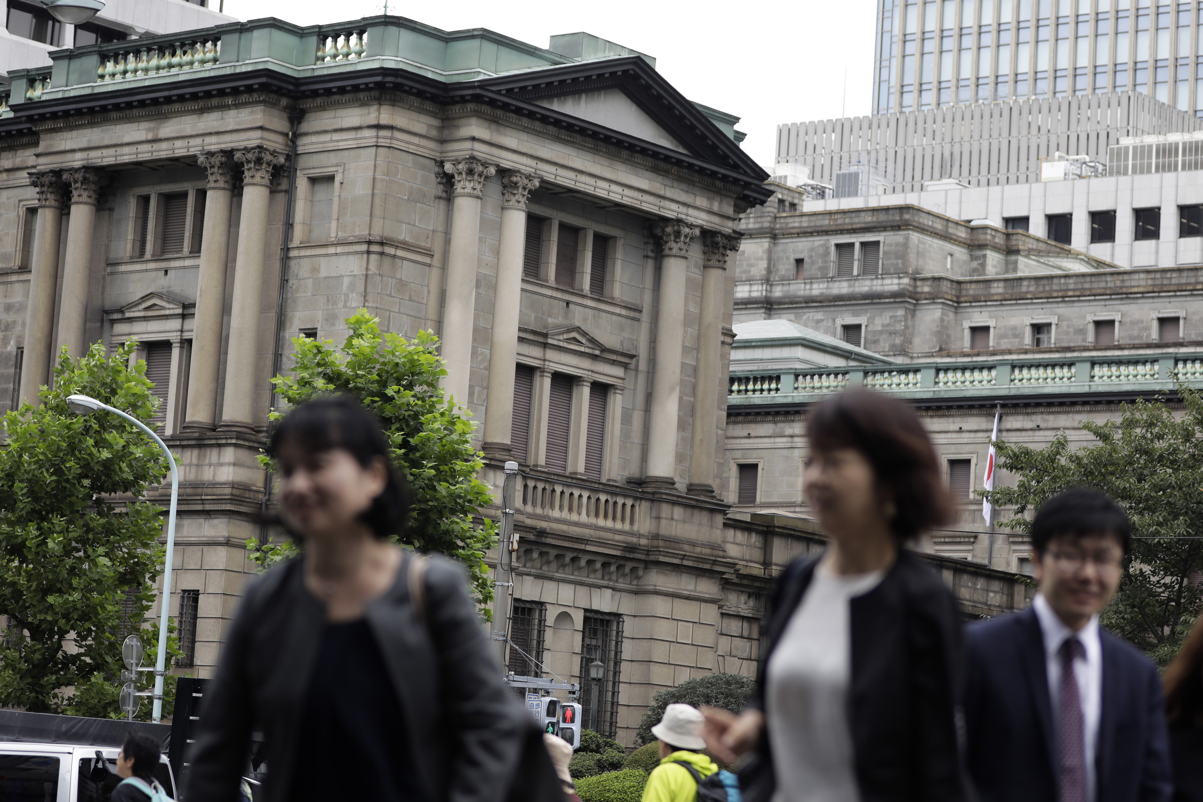 Pedestrians walk past the Bank of Japan headquarters in Tokyo in September 2016.  | BLOOMBERG