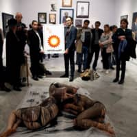 Extinction Rebellion members lie on the floor, covered in fake crude oil, to protest an exhibition sponsored by BP at The National Portrait Gallery in London Sunday. | REUTERS