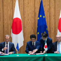 Prime Minister Shinzo Abe, flanked by European Union President Donald Tusk (left) and Jean-Claude Juncker, president of the European Commission, sign the Japan-EU free trade agreement at the Prime Minister\'s Office in Tokyo in July 2018. | VIA BLOOMBERG
