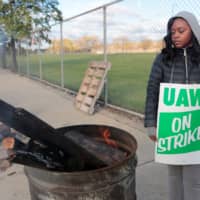 Striking United Auto Workers (UAW) member Anesha Towell keeps warm at a burn barrel while picketing at the General Motors Detroit-Hamtramck Assembly in Detroit Thursday. | REUTERS