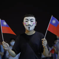 A man holds Taiwanese flags as he join others at a rally to mark Taiwan\'s National Day, in the Tsim Sha Tsui district in Hong Kong Thursday. A Hong Kong government official said on Thursday that Apple was responsible for removing a smartphone application that allowed activists to report police movements. | AP