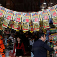 Shoppers at a store in Tokyo on Sept. 25 browse beneath banners warning of the imminent rise in the consumption tax. | REUTERS