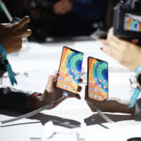 Attendees take photographs of new Huawei Mate 30 smartphones during the device\'s unveiling in Munich in September. | BLOOMBERG