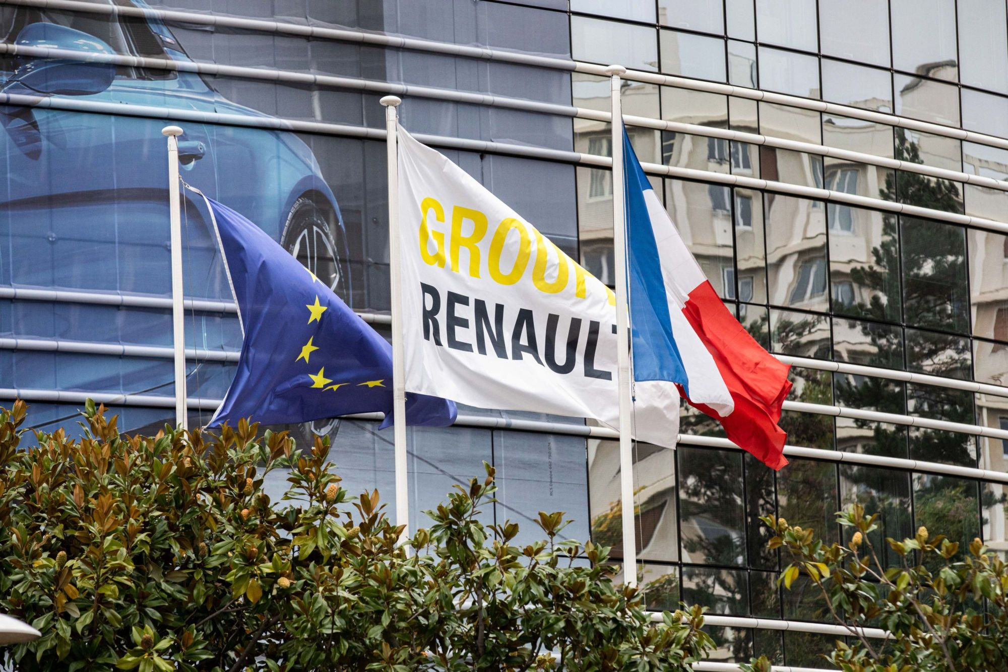 A Group Renault flag flies between a European Union flag and a France national flag outside the Renault SA headquarters in Paris. | BLOOMBERG