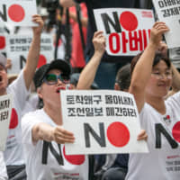 Protesters hold placards reading \"No Abe!\" during a demonstration in Seoul in August against Japan\'s removal of South Korea from a list of trusted trading partners. | BLOOMBERG