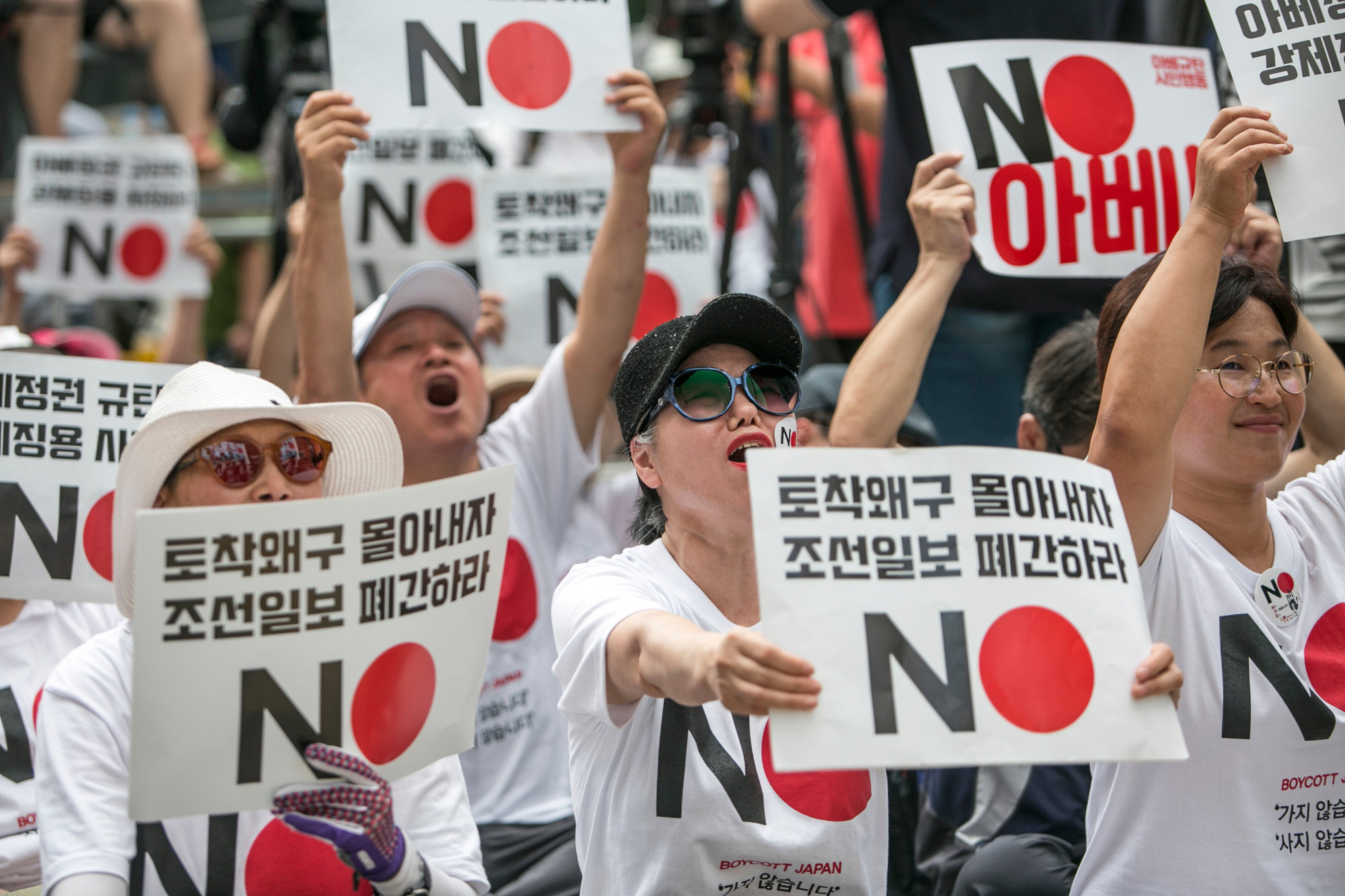 Protesters hold placards reading 'No Abe!' during a demonstration in Seoul in August against Japan's removal of South Korea from a list of trusted trading partners. | BLOOMBERG