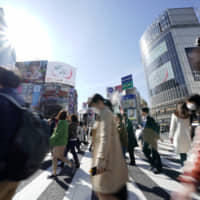 People cross an intersection in Tokyo\'s Shibuya district in March. | BLOOMBERG