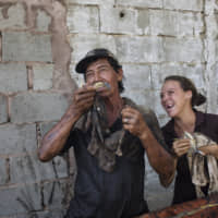 Fisherman Antonio Tello jokes around with his daughter, Genesis Tello, as they clean oil off of crabs that he caught in Lake Maracaibo, on Punta Gorda beach in Cabimas, Venezuela, in July. | AP