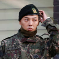 G-Dragon, the leader of the South Korean boy band Big Bang, emerges after being discharged from the army in Yongin, South Korea, on Saturday. | REUTERS