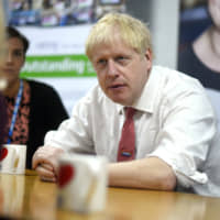 British Prime Minister Boris Johnson speaks to mental health professionals during his visit to Watford General Hospital, in Watford, England, Monday. Britain and the European Union appeared to be poles apart Monday on a potential Brexit deal, with the Dutch government urging the British government to offer \"more realism and clarity,\" and  Johnson insisting the bloc has to soften its stance. | PETER SUMMERS / POOL PHOTO / VIA AP