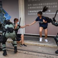 Hong Kong police chase down a couple wearing face masks in Hong Kong on Saturday, a day after the city\'s leader outlawed face coverings at protests invoking colonial-era emergency powers not used for half a century. | AFP-JIJI