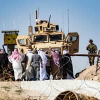 Syrian Kurds take part in a demonstration against Turkish threats at a U.S.-led international coalition base on the outskirts of Ras al-Ain town in Syria\'s Hasakeh province near the Turkish border on Sunday. Ankara reiterated on Saturday an oft-repeated threat to launch an \"air and ground\" operation in Syria against a Kurdish militia it deems a terrorist group. | AFP-JIJI