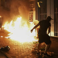 A protester throws a gasoline bomb outside the Tsuen Wan police station in Hong Kong on Wednesday. | AP