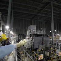 Members of the media tour inside the multinuclide removal facility, or advanced liquid processing system (ALPS), used for treating contaminated water accumulated, during a media tour of Tokyo Electric Power Co\'s crippled Fukushima No. 1 nuclear power plant in Okuma, Fukushima Prefecture, Oct. 2. | BLOOMBERG