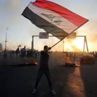 A protester waves the Iraqi flag during a demonstration against state corruption, failing public services and unemployment in Baghdad on Saturday. | AFP-JIJI