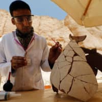 An Egyptian archaeologist works on objects from the Valley of the Monkeys in Luxor on Thursday. | REUTERS