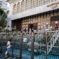 A pedestrian looks at the entrance to the Kowloon Mosque covered in blue-dyed liquid sprayed by a police water cannon vehicle during a protest in the Tsim Sha Tsui district of Hong Kong on Sunday. | BLOOMBERG