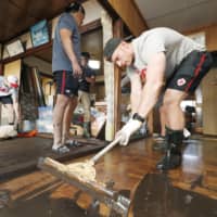 Canadian player Peter Nelson helps to clean up mud inside a house in Kamaishi, Iwate Prefecture, on Sunday, following the cancelation of a Rugby World Cup Pool B match against Namibia due to a powerful typhoon. | REUTERS