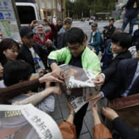 A newspaper worker hands out copies of an extra edition reporting the enthronement ceremony in Tokyo. | AP