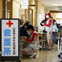 Members of the Japanese Red Cross Society work at a medical booth at an evacuation center in Rikuzentakata City, Iwate Prefecture, in April 2011, a month after a major earthquake struck the region. | BLOOMBERG
