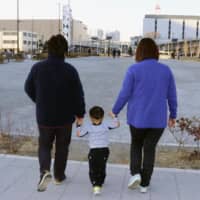 A lesbian couple walk with their child in the city of Saitama in January. They found a sperm donor via the internet. | KYODO