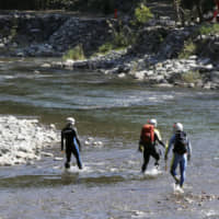 Yamanashi Prefectural Police officials search Wednesday along the Doshi River in Sagamihara, Kanagawa Prefecture, for traces of a missing 7-year-old girl. | KYODO
