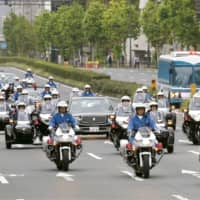 Cars and motorcycles make their way down a road in Tokyo on Sunday during a parade rehearsal Oct. 22 to mark Emperor Naruhito\'s enthronement. | KYODO