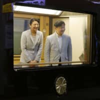 Emperor Naruhito and Empress Masako are pictured aboard a special train bearing the imperial chrysanthemum crest at Hitachi Station in Ibaraki Prefecture on Sunday. | KYODO